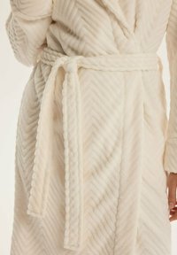 Biała puchowa szlafrok z wzorem w chevron, z wiązanym paskiem i teksturowanym materiałem, wykończony pluszowym obszyciem na brzegach i rękawach.