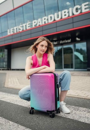 Tvrdá kufr s gradientním designem od růžové po tyrkysovou, s texturovanými vzory a čtyřmi otočnými koly pro snadnou manipulaci.