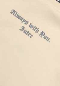 Felpa beige con testo grigio che recita “Sempre con te. Juter” in un carattere decorativo, con un aspetto di tessuto testurizzato.