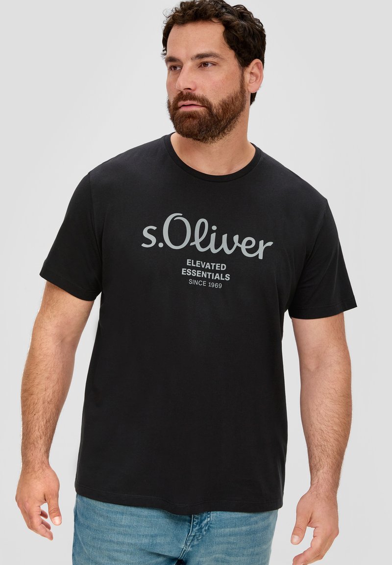 Mustmustriistest t-särk, millel on ümar kaelus, hall "s.Oliver" logo ja tekst "ELEVATED ESSENTIALS SINCE 1969", lühikesed varrukad.