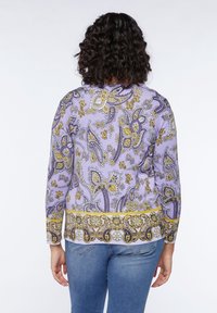 Blůza s dlouhým rukávem ve světle fialové barvě, zdobená složitými paisley a květinovými vzory ve žluté a tmavě fialové barvě. Měkká látka se standardním střihem.