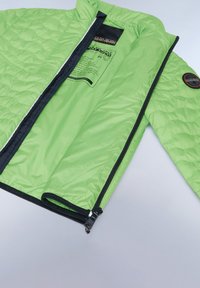 Giacca trapuntata verde con zip nera e rifiniture, dotata di un'etichetta interna e di un patch sul braccio. Leggera e con una texture morbida.