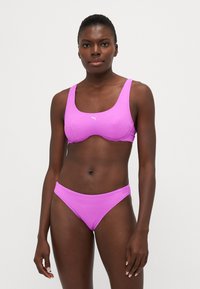 Violet bikini komplektas, pagamintas iš tekstūruotos medžiagos. Viršus turi kvadratinį iškirpimą ir plačias petnešas, o apatinė dalis yra žema, su lygiu kirpimu.