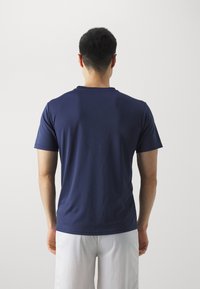 Mørkeblå kortermet t-skjorte med rund hals, laget av glatt stoff, med en tettsittende passform og minimale sømmer på baksiden.