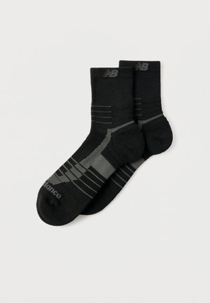 Pair of black New Balance athletic socks with gray accents and logo, ribbed cuffs, and reinforced heel and toe areas.