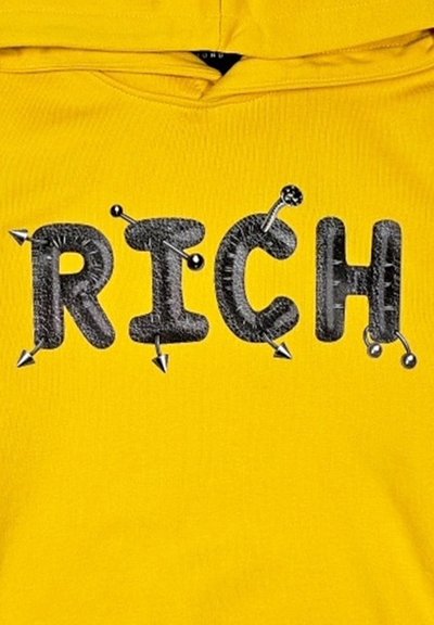 Felpa gialla con la parola "RICH" in nero dal finish texturizzato, accentuata da borchie e spille sulle lettere.