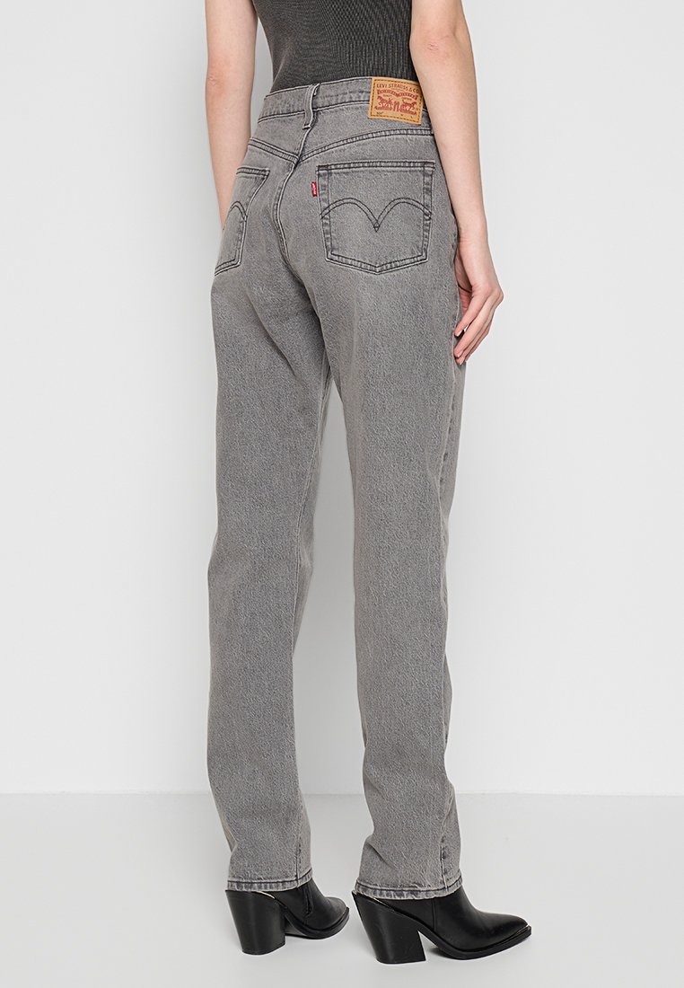 Jeans de denim gris con pierna recta, que cuentan con dos bolsillos traseros, una etiqueta de cuero en la cinturilla y una sutil textura desgastada.