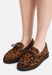 Brune leopardmønstrede mokkasin-style sko med en blød tekstur og brune snøre detaljer, placeret på en mørk gummisål.