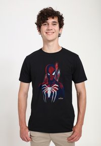 Svart t-shirt med en grafik av Spider-Man i röda och blå nyanser, som visar nätmönster och detaljerade ansiktsdrag.