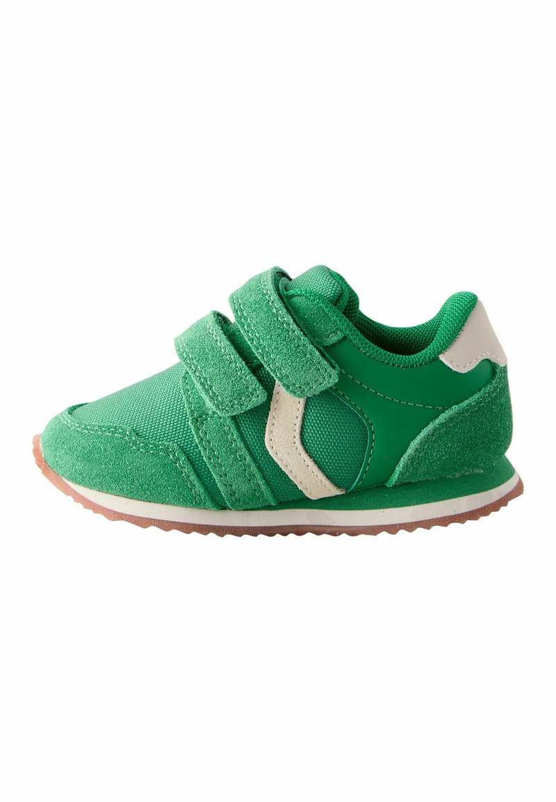 Zielony but sportowy z teksturowanym materiałem i zamszowym wykończeniem. Posiada dwa zapięcia na rzep i gumową podeszwę, akcentowaną białymi detalami.