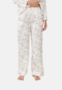 Pantalones de pijama de algodón con un fondo crema, que presentan un patrón juguetón de gatos y cintas en azul y rosa. Corte holgado con cintura elástica.