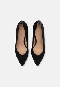 Black suede high heels with a pointed toe, low cut sides, and a smooth inner lining. Simple branding visible on the insole.