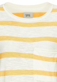 Gestreiftes T-Shirt in hellem Creme mit gelben Streifen, mit rundem Ausschnitt und einer linken Brusttasche. Weicher, strukturierter Stoff.