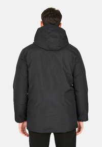 Giacca nera con cappuccio, dalla texture liscia, design leggermente oversize e taglio lungo, caratterizzata da un'estetica minimalista e priva di logo visibili.