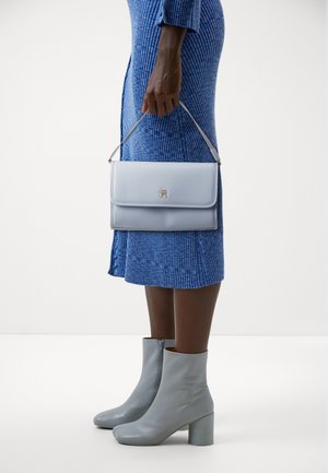 Helles blaues Lederhandtasche mit silberner Hardware, rechteckiger Form und einem oberen Griff, kombiniert mit knielangen hellgrauen Stiefeln mit Absatz.