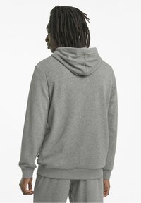 Sudadera gris hecha de tela suave, con una gran capucha, puños y cintura acanalados, con un corte relajado y diseño minimalista.