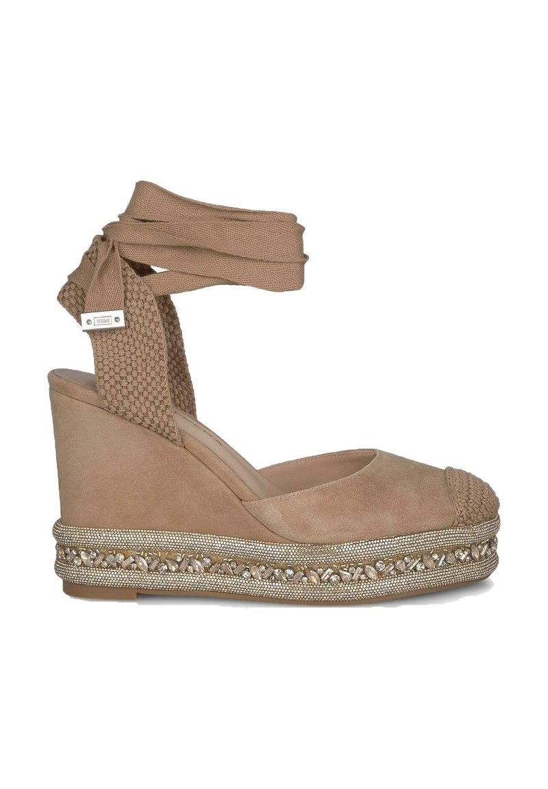 Beige suède wedge espadrille met gevlochten neusstuk, textuur enkelband en versierde jute platform met metalen accenten.