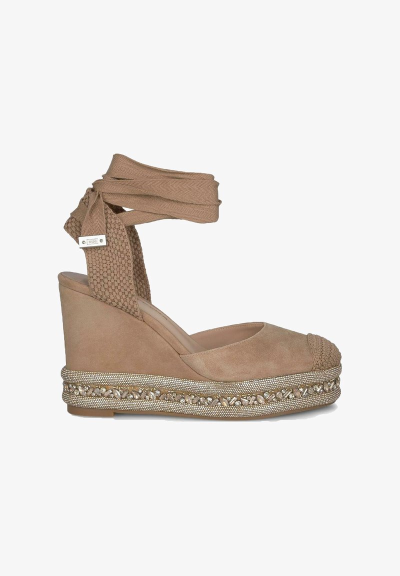 Beige suède wedge espadrille met gevlochten neusstuk, textuur enkelband en versierde jute platform met metalen accenten.