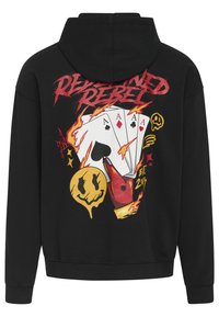Schwarze Kapuzenjacke mit einem bunten Grafikdesign auf dem Rücken, das Spielkarten, Flammen und ein lächelndes Gesichtssymbol enthält.