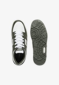 Sneaker Lacoste con tomaia in pelle bianca e verde scuro, chiusura con lacci, suola in gomma testurizzata e dettaglio del logo sul lato.