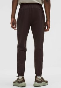 Braune, leichte Jogginghose mit elastischem Bund und schmal zulaufendem Bein, mit Reißverschlussabschlüssen und Hosentaschen.