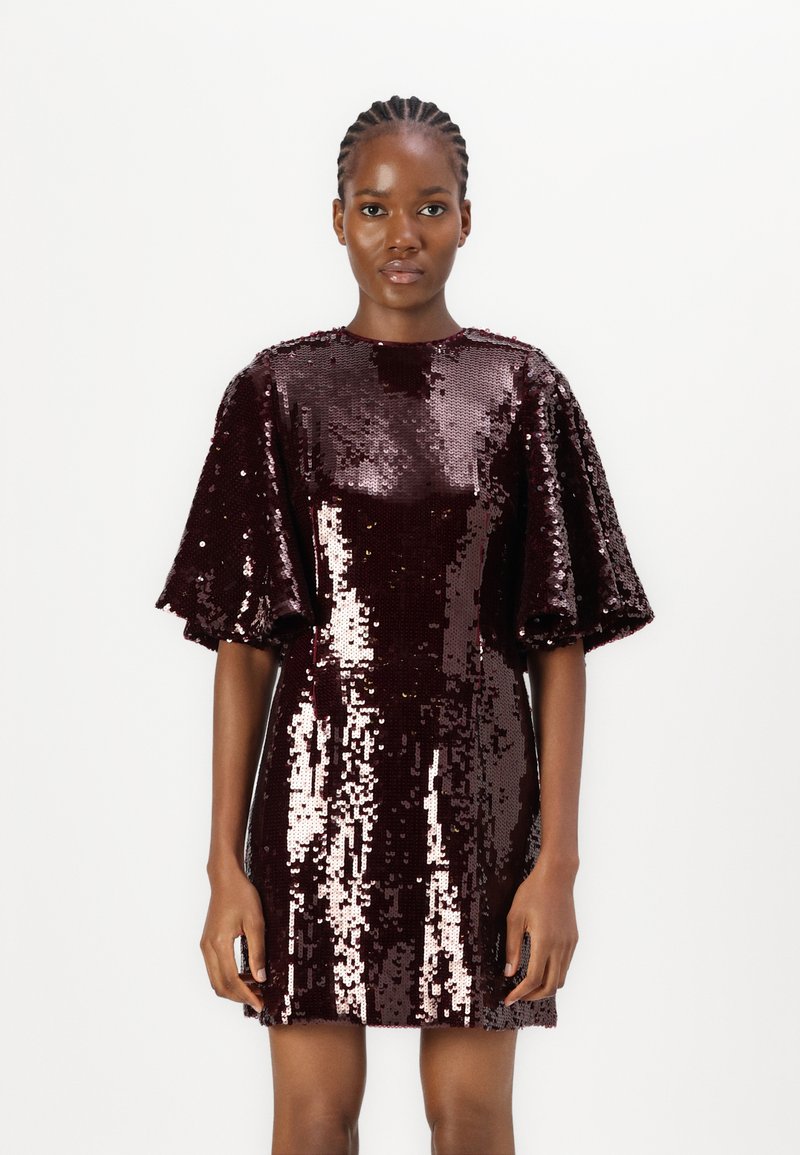 Robe en sequins bordeaux avec une silhouette carrée, des manches bouffantes courtes et un col rond. Les sequins créent une surface lisse et texturée.