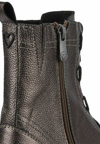 Bottine en cuir marron avec une finition texturée, dotée d'une fermeture éclair sur le côté et d'un accent en forme de cœur sur la tirette. Design à lacets inclus.