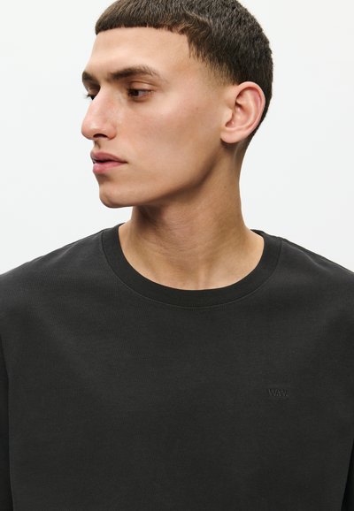 Tricou din bumbac negru, cu guler rotund și mâneci scurte, având un detaliu subtil cu logo pe piept, textură fină și croială clasică.