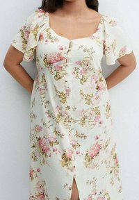 Robe florale en crème avec des manches courtes bouffantes, ornée de motifs de fleurs roses et vertes, d'un décolleté carré et d'une fermeture à boutons sur le devant.
