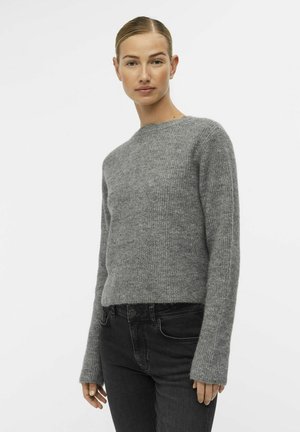 Grå strikkegenser med rund hals, lange ermer og avslappet passform. Teksturen er litt fluffy, kombinert med svarte jeans.