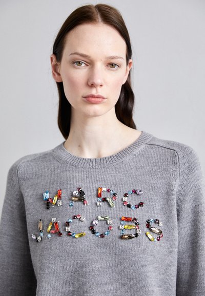 Suéter gris con "MARC JACOBS" en coloridos y embellidos cristales. El diseño incluye un cuello redondo y un tejido de punto texturizado.
