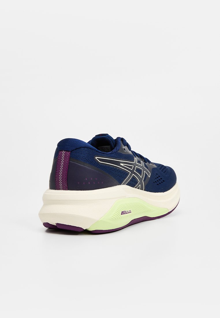 Marineblaue Laufschuhe mit weißen und lila Akzenten, dicker weißer Sohle mit hellgrünen Details, Schnürverschluss und Obermaterial aus Mesh für Atmungsaktivität.