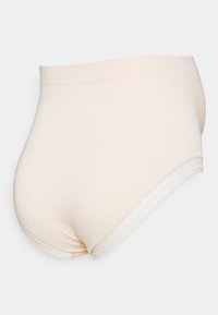 Culotte taille haute beige sans coutures avec une texture lisse et une taille élastique, présentant des coutures discrètes et une silhouette arrondie.
