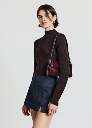 Brauner Strickpullover mit hohem Kragen, blau karierter Minirock mit Frontrissen und eine burgunderrote Leder-Umhängetasche mit silberner Schnalle.