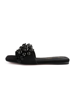 Mules noires avec un dessus en tissu texturé, orné d'un accent froncé et d'un cluster de perles noires brillantes à l'avant. Semelle plate.