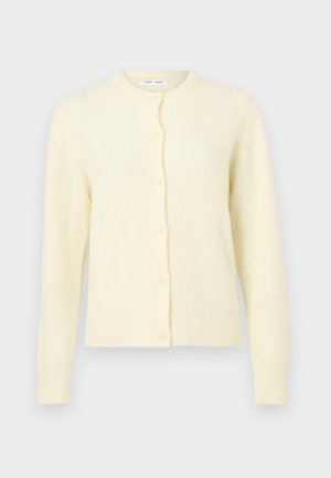 Kerge kollase tooniga nööpidega kardigan pehme tekstuuriga, ümara kaelusega ja pikkade varrukatega. Ees kuus nööpi ja soonikuäärsed mansetid.