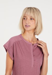 Korte mouwen, rozenkleurig topje met een ronde hals en knoopsluiting aan de voorkant. Gemaakt van zachte, lichtgewicht stof met een relaxte pasvorm.