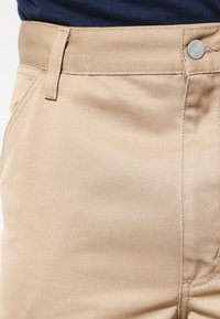 Beige katoenmengsel broek met een gladde textuur, voorzien van een knoopsluiting, riemlussen en verticale stikdetails.
