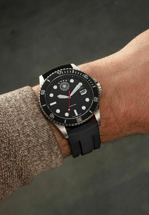 Black dive watch with a stainless steel case, rubber strap, white markers, and red second hand. Features a date window and rotating bezel.