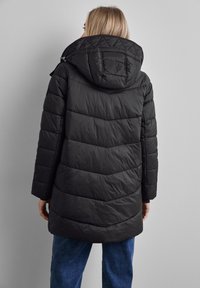 Svart vadderad jacka med huva, med horisontella quiltade sektioner och knälång design. Materialet verkar glänsande, lätt och slätt.