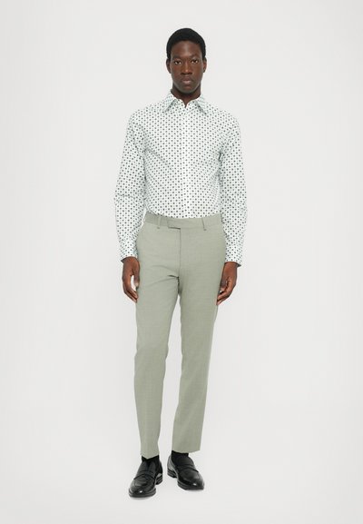 White long-sleeve shirt with black polka dots, paired with light green tapered trousers and black loafers. Simple design, smooth fabric.