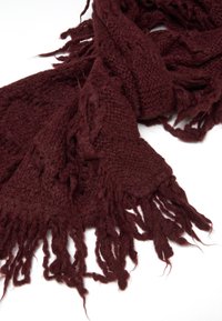 Sciarpa lavorata a maglia bordeaux con una trama texturizzata e lunghi lati sfrangiati. Il materiale appare morbido e caldo.
