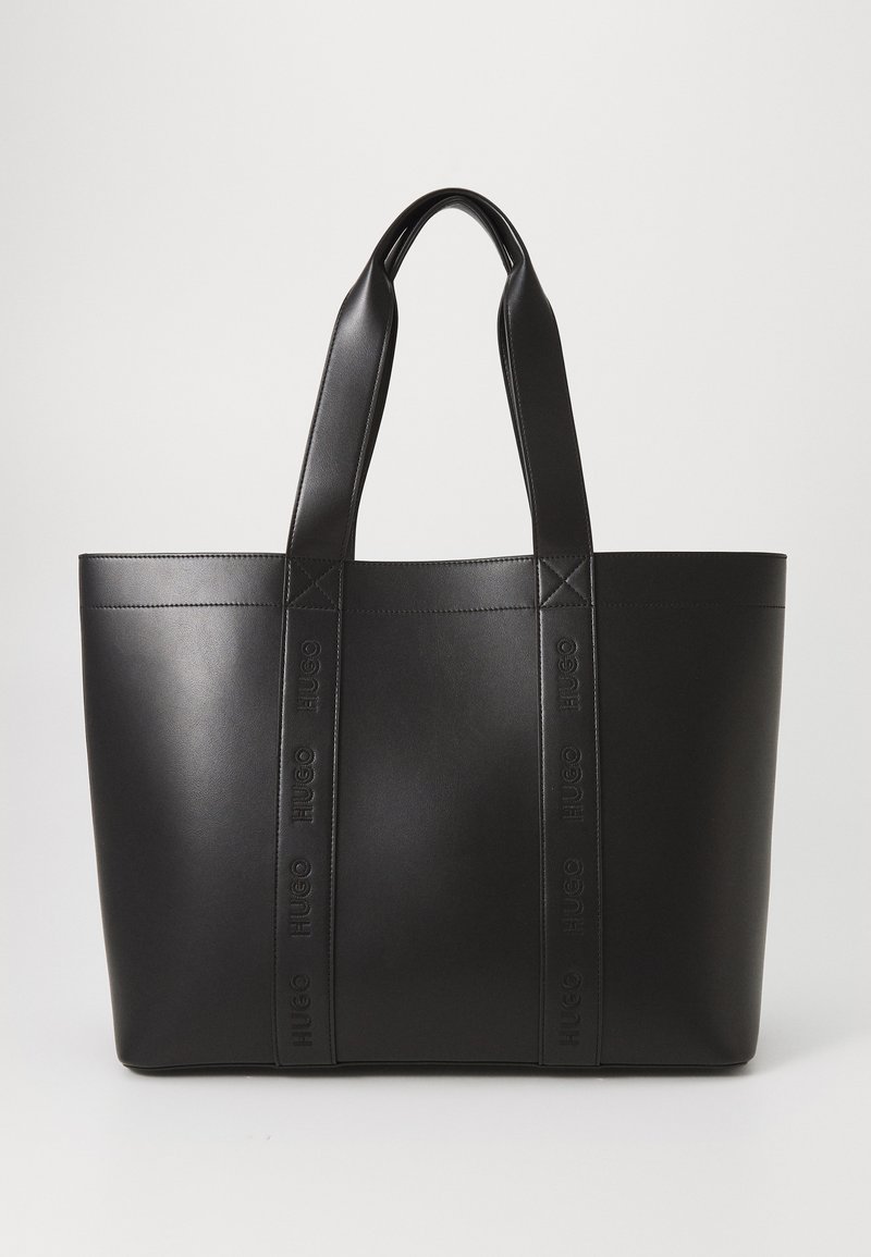 Sac fourre-tout en cuir noir avec double anses supérieures. Doté du nom de la marque embossé sur les côtés, texture lisse et design minimaliste.