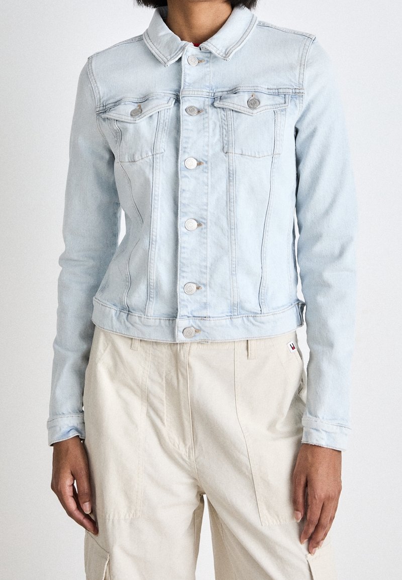 Light blue denim jacket with a button-up front, chest pockets, and a cropped design. Features a collared neck and subtle stitching details.