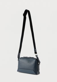 Μικρό δερμάτινο τσαντάκι ώμου σε ναυτικό μπλε χρώμα, με μαύρο ρυθμιζόμενο λουρί που φέρει την επιγραφή "LANCEL", ασημένιο φερμουάρ και μεταλλικά εξαρτήματα.