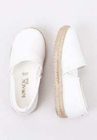 Zapatos slip-on de lienzo blanco con una suela de yute tejido texturizado, que presentan una punta redonda y un diseño minimalista.