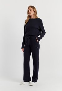 Set di maglione navy e pantaloni abbinati realizzati in morbido tessuto a maglia. I pantaloni presentano un elastico in vita con coulisse e tasche laterali.