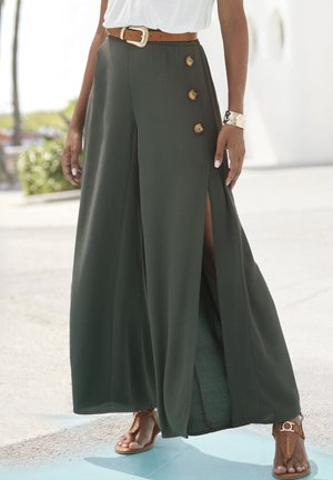 Wide-leg, olive green trousers with front slits, gold button details, and a high waist. Worn with a brown belt and brown sandals.