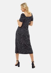 Black and gray zebra-patterned midi dress with puff sleeves, square neckline, and a fitted silhouette. Worn with high-heeled sandals.
