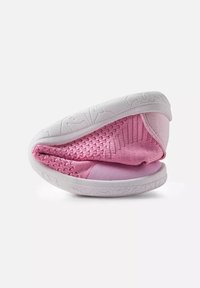 Baskets roses tricotées flexibles pliées en deux pour montrer leur douceur, avec une semelle blanche épaisse et texturée sur un fond blanc.